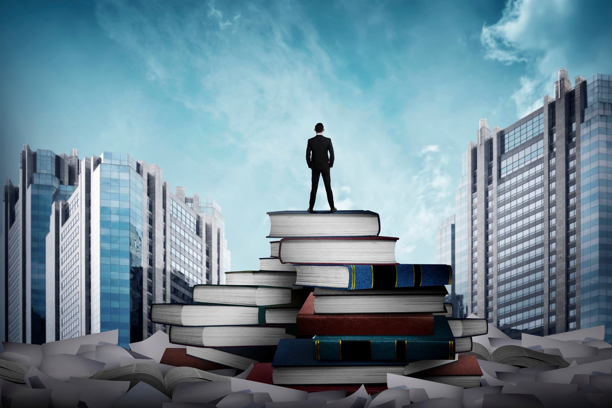 Business-man-standing-on-the-top-of-books-524029540_2125x1416